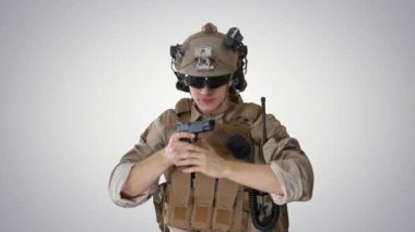 Ordu elit güçlerinin askeri, meyilli arka planda tabancayla yürüyor ve ateş ediyor..