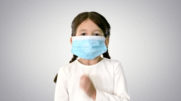 Bambina che indossa maschera protettiva prendendo respiri profondi guardando la fotocamera su sfondo sfumato. — Video Stock