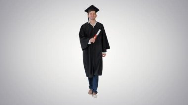 Mezuniyet cübbesi içinde gülümseyen erkek öğrenci, arka planda diplomasıyla yürüyor..