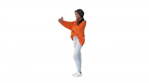 Smiling african american woman in bright jumper taking selfie and checking her phone on white background. — Stock Video
