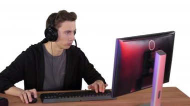 Kulaklıklı oyuncu bilgisayarda video oyunu oynuyor ve beyaz arka planda kazanıyor..