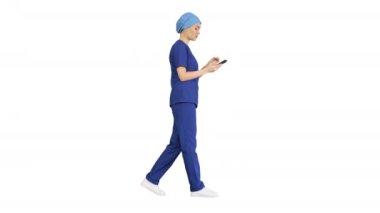 Beyaz arka planda yürürken telefonunu kullanan mavi üniformalı kadın doktor ya da hemşire..
