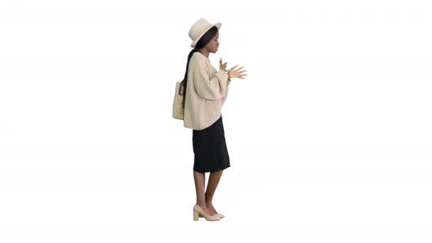 Jeune femme afro-américaine en tricot et chapeau blanc parlant et gesticulant sur fond blanc. — Video