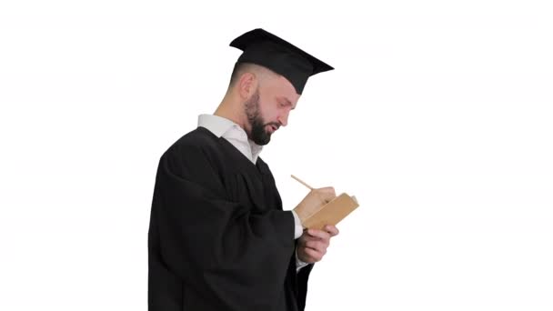 Homme de graduation réfléchi écrivant ses objectifs sur fond blanc. — Video