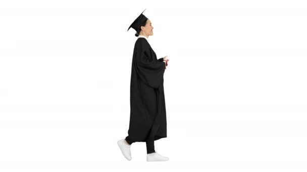 Happy female student in graduation robe walking and cheering with her diploma on white background. — Stock Video