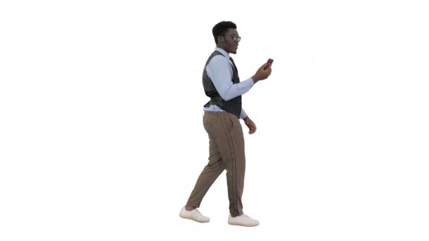 Sorrindo empresário afro-americano fazendo videochamada segurando celular em sua mão enquanto caminhava no fundo branco. — Vídeo de Stock
