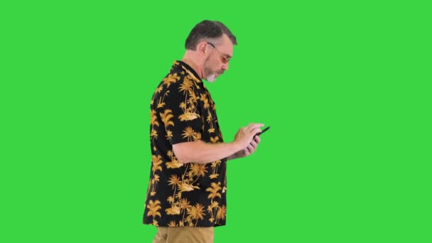 Yeşil Ekran, Chroma Key 'de yürüyen ve akıllı telefon kullanan kıdemli turist.. — Stok video