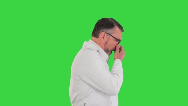 Tired senior doctor in glasses walking on a Green Screen, Chroma Key. — Stock Video
