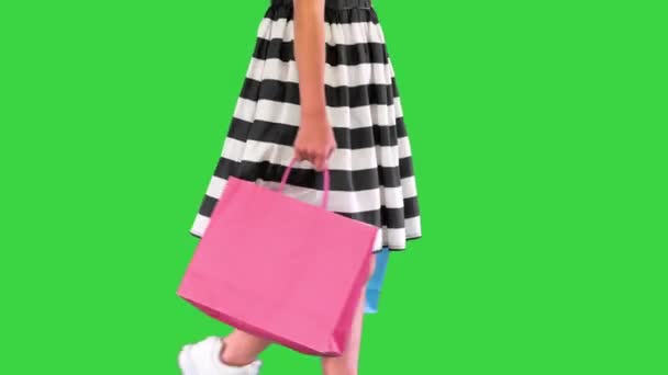 Liten flicka promenader med shoppingväskor på en grön skärm, Chroma Key. — Stockvideo