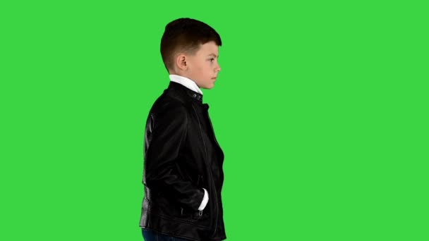 Мальчик в кожаной куртке ходит с руками в карманах на зеленом экране, хрома ключ. — стоковое видео