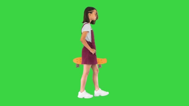 Gadis yang memegang skateboard dan berjalan di layar hijau, Chroma Key. — Stok Video