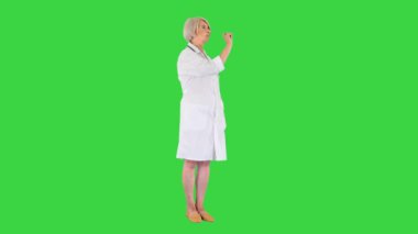 Sağlık, tıp ve teknoloji konsepti - Kıdemli kadın doktor bir şeye işaret ediyor veya yeşil ekrandaki hayali düğmelere basıyor, Chroma Key.