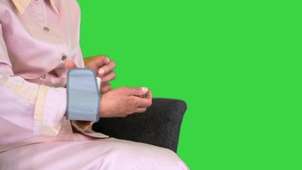 Ηλικιωμένη γυναίκα που μετρά την αρτηριακή πίεση σε μια πράσινη οθόνη, Chroma κλειδί. — Αρχείο Βίντεο