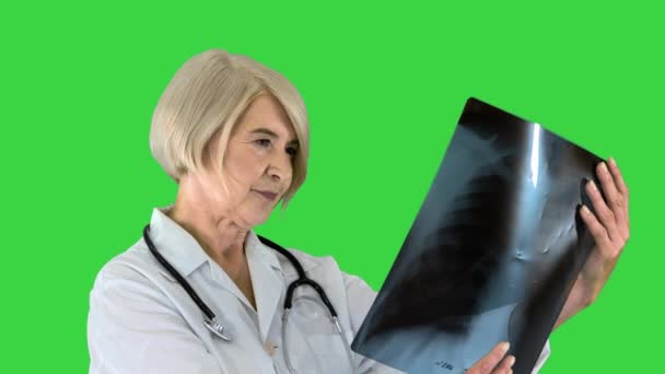 緑の画面上の肺X線を見ているシニア女性医師,クロマキー. — ストック動画