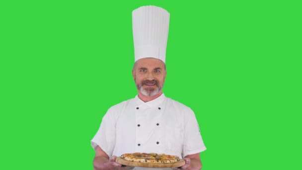 Ανώτερος αρσενικό επικεφαλής μάγειρας με στολή κρατώντας πίτσα σε μια πράσινη οθόνη, Chroma Key. — Αρχείο Βίντεο