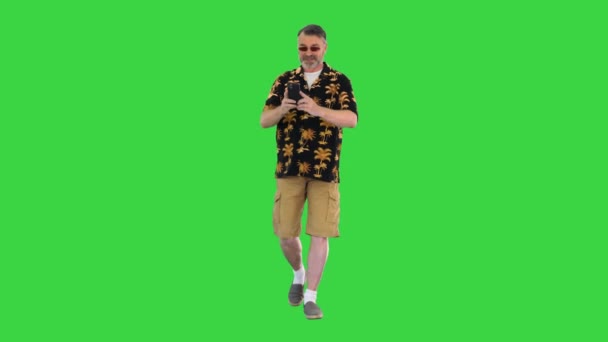 Glimlachende reiziger toerist bejaarde grijze man schieten op mobiele telefoon tijdens het lopen op een groen scherm, Chroma Key. — Stockvideo