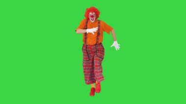 Kırmızı kıyafetli mutlu palyaço yeşil ekranda geziniyor, Chroma Key..