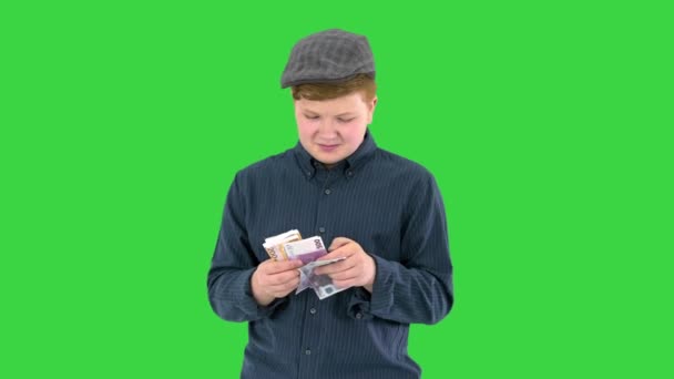 Rijk tiener in een cap tellen euro 's op een groen scherm, Chroma Key. — Stockvideo