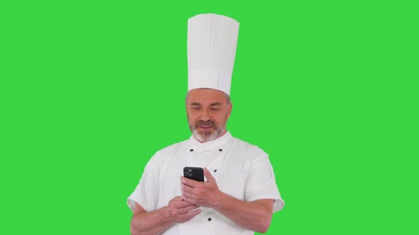 Chef masculino haciendo una videollamada en un smartphone en una pantalla verde, Chroma Key. — Vídeos de Stock