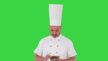 Kıdemli erkek aşçı Yeşil Ekran, Krom Anahtar hakkında notlar alıyor..