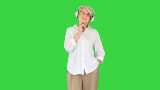 Vieille dame avec écouteurs écoutant une belle mélodie sur un écran vert, Chroma Key. — Video