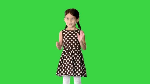 Carino bambina in abito a pois battendo le mani guardando la fotocamera su uno schermo verde, Chroma Key. — Video Stock