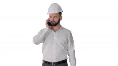Beyaz arka planda yürürken telefonla konuşan mimar.