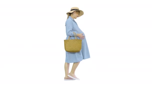 漂亮的孕妇头戴大帽子，背着白色的背景，走路，摸着肚子. — 图库视频影像