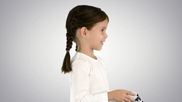 Lächelndes kleines Mädchen spielt Videospiel mit Steuerknüppel in der Hand auf dem Hintergrund des Gefälles. — Stockvideo