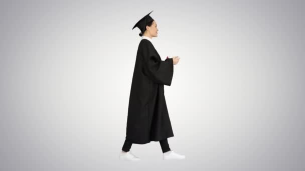 Graduada femenina enérgica caminando con diploma y dando un discurso motivador sobre el fondo del gradiente. — Vídeo de stock