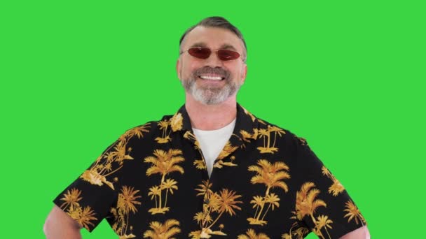 Vellykket gammel mann i solbriller på ferie med kamera på en grønn skjerm, Chroma Key. – stockvideo