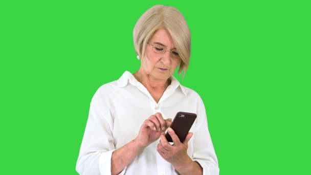Senior vrouw dame met behulp van smartphone op een groen scherm, Chroma Key. — Stockvideo