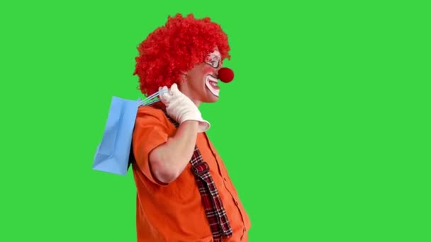 带着购物袋走在绿色屏幕上的滑稽小丑，Chroma Key. — 图库视频影像