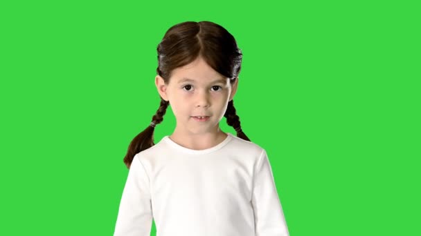 Nieśmiała dziewczynka z ogonami świni ubrana w biały top z długim rękawem spacerująca i patrząca w dół na jej stopy i kamerę na zielonym ekranie, Chroma Key. — Wideo stockowe
