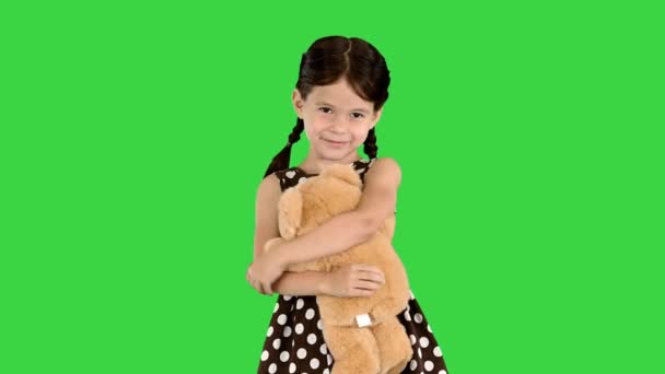 Klein meisje in polka dot jurk knuffelen teddybeer echt strak glimlachen op camera op een groen scherm, Chroma Key. — Stockvideo