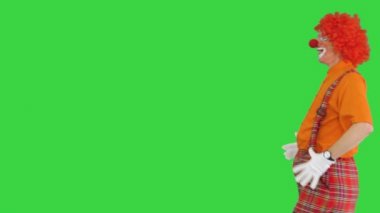 Palyaço yürüyor ve yeşil ekran, Chroma Key 'deki kameraya komik bir bakış atıyor..