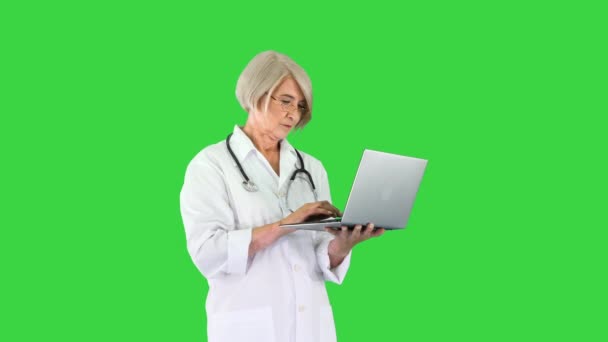 Γιατρός γυναίκα στέκεται και εργάζεται σε ένα φορητό υπολογιστή σε μια πράσινη οθόνη, Chroma κλειδί. — Αρχείο Βίντεο