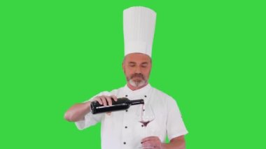 Kıdemli aşçı yeşil ekranda kırmızı şarap tadıyor, Chroma Key.