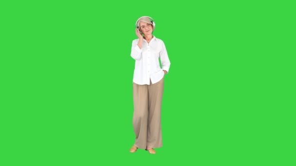 Старшая женщина слушает музыку с наушниками на зеленом экране, Chroma Key. — стоковое видео