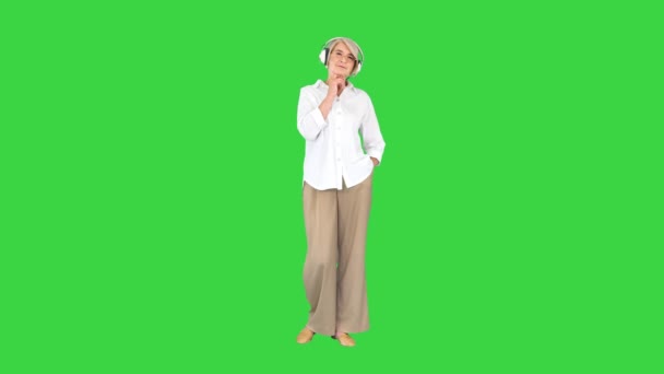 Anciana con auriculares escuchando una hermosa melodía en una pantalla verde, Chroma Key. — Vídeos de Stock
