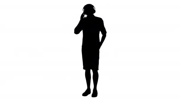 Silhouette Casual young man listening to music holding headphones by his hand. — Stock Video