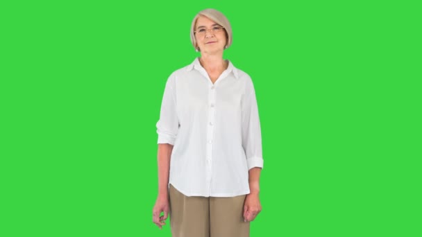 Gelukkig oud senior vrouw modern oma in bril kijken naar camera op een groen scherm, Chroma Key. — Stockvideo