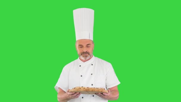 Starszy kucharz z pizzą w ręku spacerujący po zielonym ekranie, Chroma Key. — Wideo stockowe