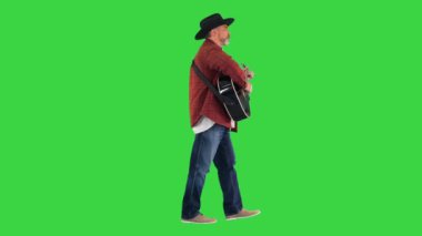 Yeşil Ekranda yürüyen ve gitar çalan kovboy şapkalı adam, Chroma Key.