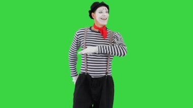 Pandomimci gülümseyip Yeşil Ekran, Krom Anahtar 'da yürüme simülasyonu yapıyor.