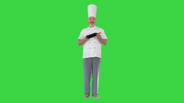 Szef kuchni w mundurze trzymając butelkę wina i rozmawiając o tym z tobą na zielonym ekranie, Chroma Key. — Wideo stockowe