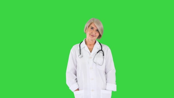 Senior läkare står med händerna vikta och ser till kameran på en grön skärm, Chroma Key. — Stockvideo