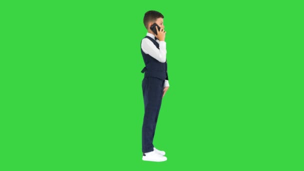 Serieuze jongen in een wit shirt, strikje en vest praten aan de telefoon op een groen scherm, Chroma Key. — Stockvideo