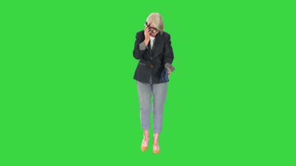 Senior zakenvrouw maakt een oproep tijdens het lopen op een groen scherm, Chroma Key. — Stockvideo