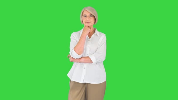 Красивая старшая леди в очках думает и имеет идею, указывая пальцем на зеленый экран, Chroma Key. — стоковое видео